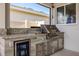 This outdoor kitchen features a granite countertop, stainless steel grill, beverage fridge, and gray wood look tile at 13299 Serene Valley Dr, Clermont, FL 34711