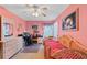 A bright bedroom with pink walls, wicker furniture, and a well-lit workspace at 1441 Olde Kensington Ln, Deltona, FL 32725
