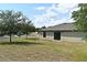 Backyard and house featuring a lush lawn, gray roof, and a sliding glass door at 35734 Rose Moss Ave, Leesburg, FL 34788