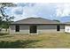 Wide shot of backyard and home with neutral color, dark roof and sliding glass door at 35734 Rose Moss Ave, Leesburg, FL 34788