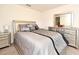 Bedroom with a queen-sized bed with decorative pillows, matching nightstands, and mirrored dressers at 35734 Rose Moss Ave, Leesburg, FL 34788