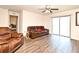 Bright living room boasts laminate flooring, ceiling fan and a plush brown leather sofa set at 35734 Rose Moss Ave, Leesburg, FL 34788