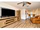 Cozy living area featuring wood flooring, a ceiling fan, a leather recliner and a large TV at 35734 Rose Moss Ave, Leesburg, FL 34788