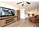 Comfortable living area featuring wood flooring, a ceiling fan, a leather recliner and a large TV at 35734 Rose Moss Ave, Leesburg, FL 34788