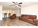 Open-concept living space featuring laminate flooring, kitchenette, ceiling fan and brown leather seating at 35734 Rose Moss Ave, Leesburg, FL 34788
