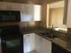 Kitchen with granite countertops, a stainless steel sink, white cabinetry, and black appliances at 495 Las Cortes Ln # 206, Orlando, FL 32824