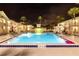 Nighttime view of the lit pool offering a relaxing atmosphere surrounded by palm trees and buildings at 5245 W Irlo Bronson Memorial Hwy # 151, Kissimmee, FL 34746