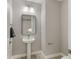 Stylish half-bathroom featuring a pedestal sink, modern lighting, and neutral colors at 724 Greybull Run, Lake Mary, FL 32746