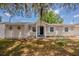 Inviting single-story home with black door, white shutters and shade trees in the front yard at 1084 Doyle Rd, Deltona, FL 32725