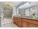 The well-lit bathroom features double sinks, granite countertops, wooden cabinets, and a shower-tub with tiled walls at 1100 Oday Dr, Winter Springs, FL 32708