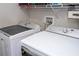 Well-equipped laundry room featuring modern washer and dryer units and shelving for storage at 11957 Vermillion Ave, Windermere, FL 34786