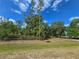 View of the property showing the front yard with a wooden fence and lush trees against a beautiful blue sky at 12454 S Lake Mary Jane Rd, Orlando, FL 32832