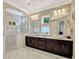 Bright bathroom featuring a marble countertop, dual sinks, a spacious glass shower, and decorative windows at 14025 Hench Ln, Orlando, FL 32827