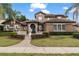 Stunning exterior showcasing a manicured lawn, mature trees, a fountain, and a tile roof at 1450 Belfiore Way, Windermere, FL 34786