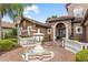 Close up of the front entrance with a decorative fountain, arched doorway, and meticulously maintained landscaping at 1450 Belfiore Way, Windermere, FL 34786