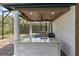 Elegant outdoor kitchen featuring a built-in grill, marble countertops, and stylish light fixtures in a screened patio at 1450 Belfiore Way, Windermere, FL 34786