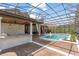 A sparkling pool is surrounded by a screened enclosure, brick pavers, manicured landscaping, and an outdoor kitchen at 1450 Belfiore Way, Windermere, FL 34786