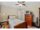 A cozy bedroom with warm colored walls, ceiling fan, and a wooden framed bed with yellow and gray patterned bedding at 1503 Canterbury Cir, Casselberry, FL 32707