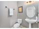 Clean, half bathroom with a modern pedestal sink, round mirror and decorative towel rack at 171 Mcleods Way, Winter Springs, FL 32708