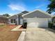 Charming single-Gathering home featuring a well-maintained lawn, attached two-car garage, and freshly painted gray exterior at 17505 Silver Creek Ct, Clermont, FL 34714