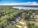 Aerial view of a neighborhood with lush green trees, single-story homes, and a serene lake in the distance at 185 Poinciana Ln, Deltona, FL 32738