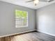 This bedroom features modern gray walls, wood flooring, and a window overlooking greenery at 185 Poinciana Ln, Deltona, FL 32738
