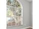 Arched window with blinds, offering a view of mature trees and a glimpse of the outdoors at 1862 Spreakley Ct, Orlando, FL 32837
