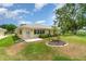 Backyard view of a cozy home with a neatly maintained lawn, garden, and a private back entrance at 21529 Prince Albert Ct, Leesburg, FL 34748