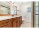 Well-lit bathroom featuring a glass-door shower, wood cabinets, neutral tile, and large framed mirror at 21529 Prince Albert Ct, Leesburg, FL 34748