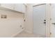 Neat laundry room with white walls, a white door, white cabinets, and light tile flooring at 21529 Prince Albert Ct, Leesburg, FL 34748