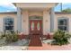Elegant front entrance featuring double doors, columns, and decorative landscaping at 235 Hollingshead Loop, Davenport, FL 33896