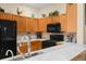 Bright kitchen featuring oak cabinets, black appliances, tile backsplash, and serving counter at 235 Hollingshead Loop, Davenport, FL 33896