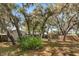 Landscaped backyard with towering shade trees, a concrete patio and wood fencing at 2935 Arcata Ln, Orlando, FL 32817
