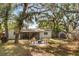 Beautiful backyard with a concrete patio with chairs, shade trees and a storage shed at 2935 Arcata Ln, Orlando, FL 32817