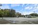 Community tennis court surrounded by mature trees with lights, next to pool house at 3154 Stonecastle Rd, Orlando, FL 32822