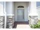 Inviting covered entry featuring stone pillars and a light gray front door with transom window and brick paving at 4548 Dulwik Pl, Sanford, FL 32771