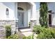 Elegant front entryway featuring stone accents, a light gray door, and brick paving, complemented by lush landscaping at 4548 Dulwik Pl, Sanford, FL 32771