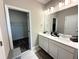 Modern bathroom featuring double sinks, white cabinets, and a view into the walk-in closet at 4828 Abbeywood Aly, Winter Garden, FL 34787