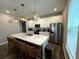 Well-lit kitchen with island seating, stainless steel refrigerator, and modern pendant lighting fixtures at 4828 Abbeywood Aly, Winter Garden, FL 34787