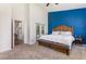 Comfortable bedroom features a king bed, blue accent wall and backyard view at 5494 Glen Oak Pl, Sanford, FL 32771