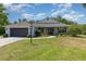 Inviting single-Gathering home with a well-kept lawn, attached garage, and a welcoming front porch with a red door at 5494 Glen Oak Pl, Sanford, FL 32771