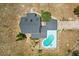 Aerial view of a home featuring a dark roof and a kidney-shaped pool, set against a backdrop of dry landscape at 6803 Round Lake Rd, Mount Dora, FL 32757