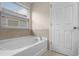 Bright bathroom featuring a soaking tub next to a window and a white door at 8554 Tallfield Ave, Orlando, FL 32832