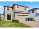 Two-story tan house featuring a two-car garage, brick paver driveway, and manicured lawn at 8554 Tallfield Ave, Orlando, FL 32832