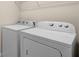 Modern white washer and dryer featuring simple knob controls and overhead storage at 8554 Tallfield Ave, Orlando, FL 32832