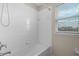 Tiled shower and bath combination featuring window and hand-held sprayer at 8554 Tallfield Ave, Orlando, FL 32832