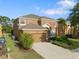 Two-story home boasts a well-manicured lawn, mature landscaping, and an attached two-car garage at 957 Orange Cosmos Blvd, Davenport, FL 33837