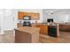 Efficient kitchen with wood cabinets, black appliances, an island, and wood-look floors at 957 Orange Cosmos Blvd, Davenport, FL 33837
