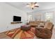 Cozy living room with comfortable leather seating, TV, modern ceiling fan, and stylish rug at 957 Orange Cosmos Blvd, Davenport, FL 33837