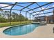 Screened-in pool and spa with view of the large, grassy backyard at 957 Orange Cosmos Blvd, Davenport, FL 33837